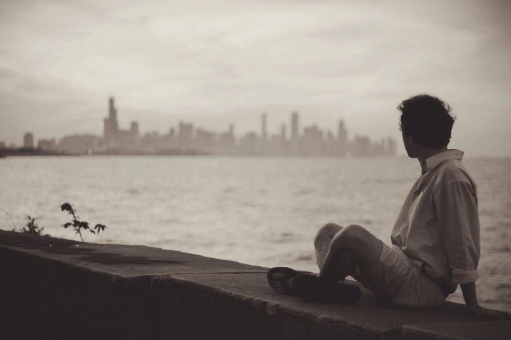 man sitting on a bridge looking sad and depressed.  Represents that Depression can be caused by complex trauma which can lead to C-PTSD.